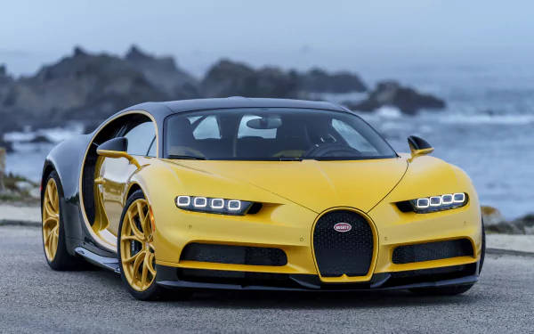 黃色Bugatti Chiron停泊在海邊道路上，背景有海浪和岩石。
