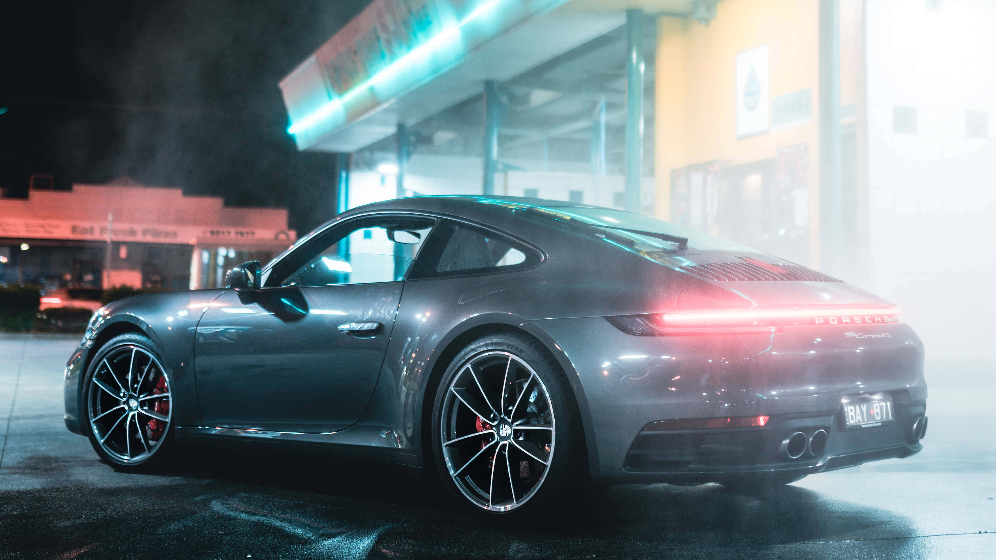 標題：Forza Horizon 4 精彩 4K 行動畫面 壁紙 — 一輛流線型灰色保時捷911在霓虹燈下閃耀，霧氣在夜間圍繞其發光的尾燈旋轉。