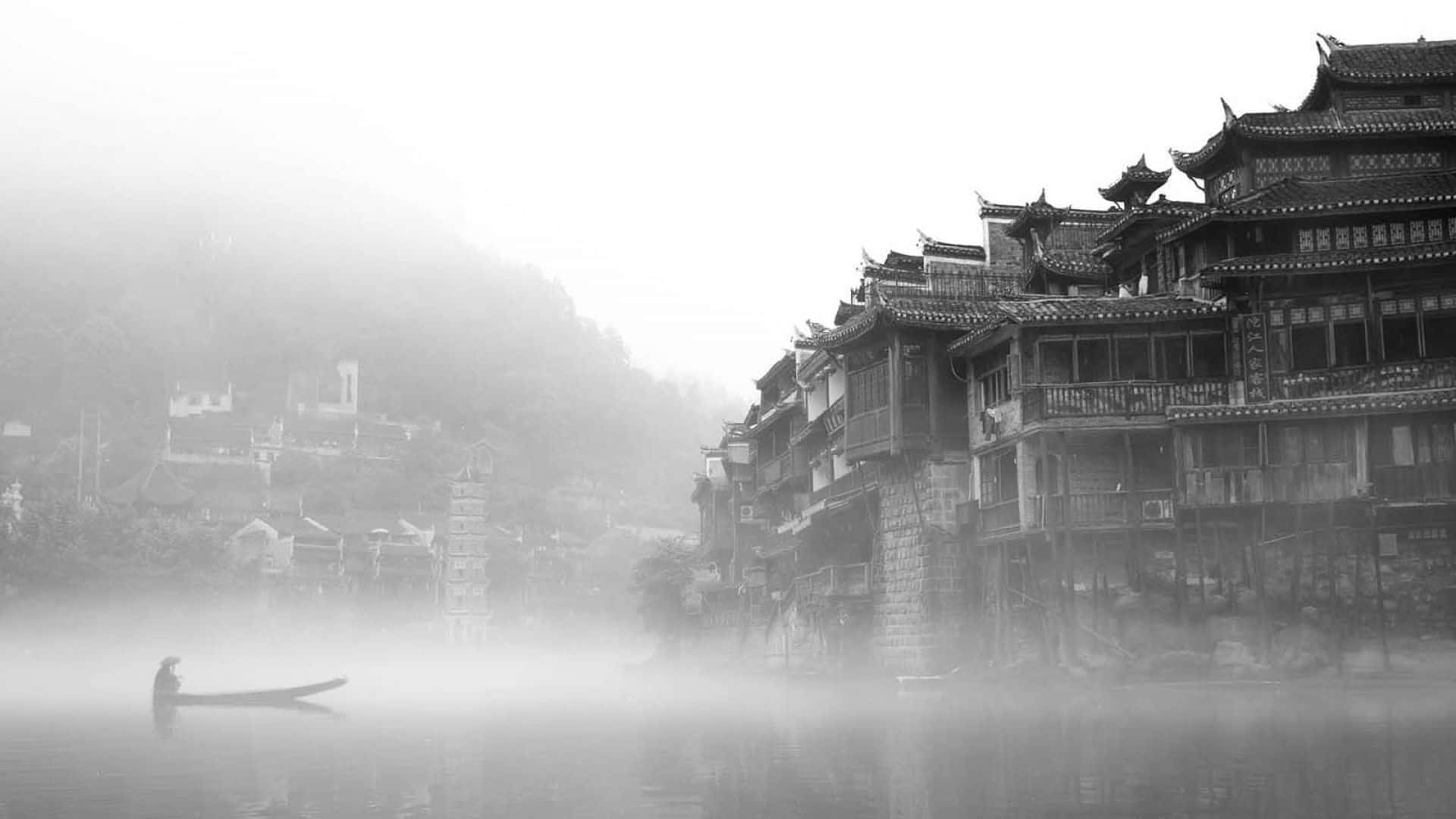 標題：中國上海令人屏息的天際線 壁紙 — 在一個霧濛濛的早晨，一個孤獨的身影在霧氣瀰漫的水面上划船，旁邊是傳統的木建築。