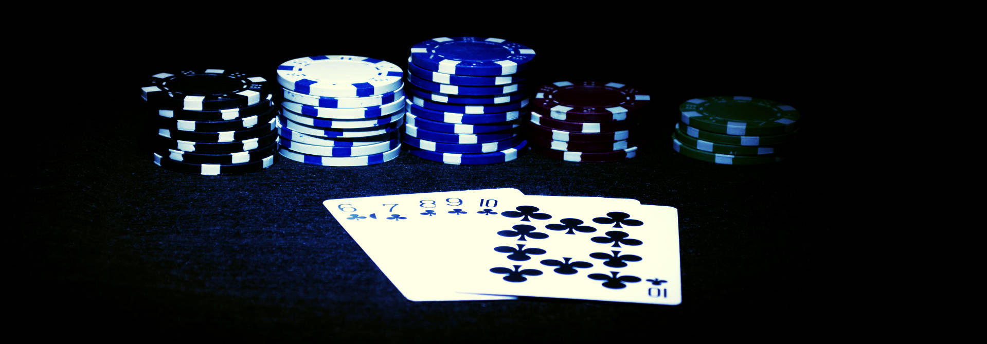 在戲劇性燈光下，深色遊戲桌上的撲克籌碼和撲克牌。