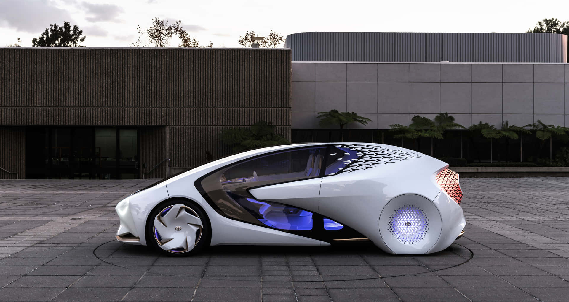 帶有藍色燈光的未來感白色汽車停在現代建築前。