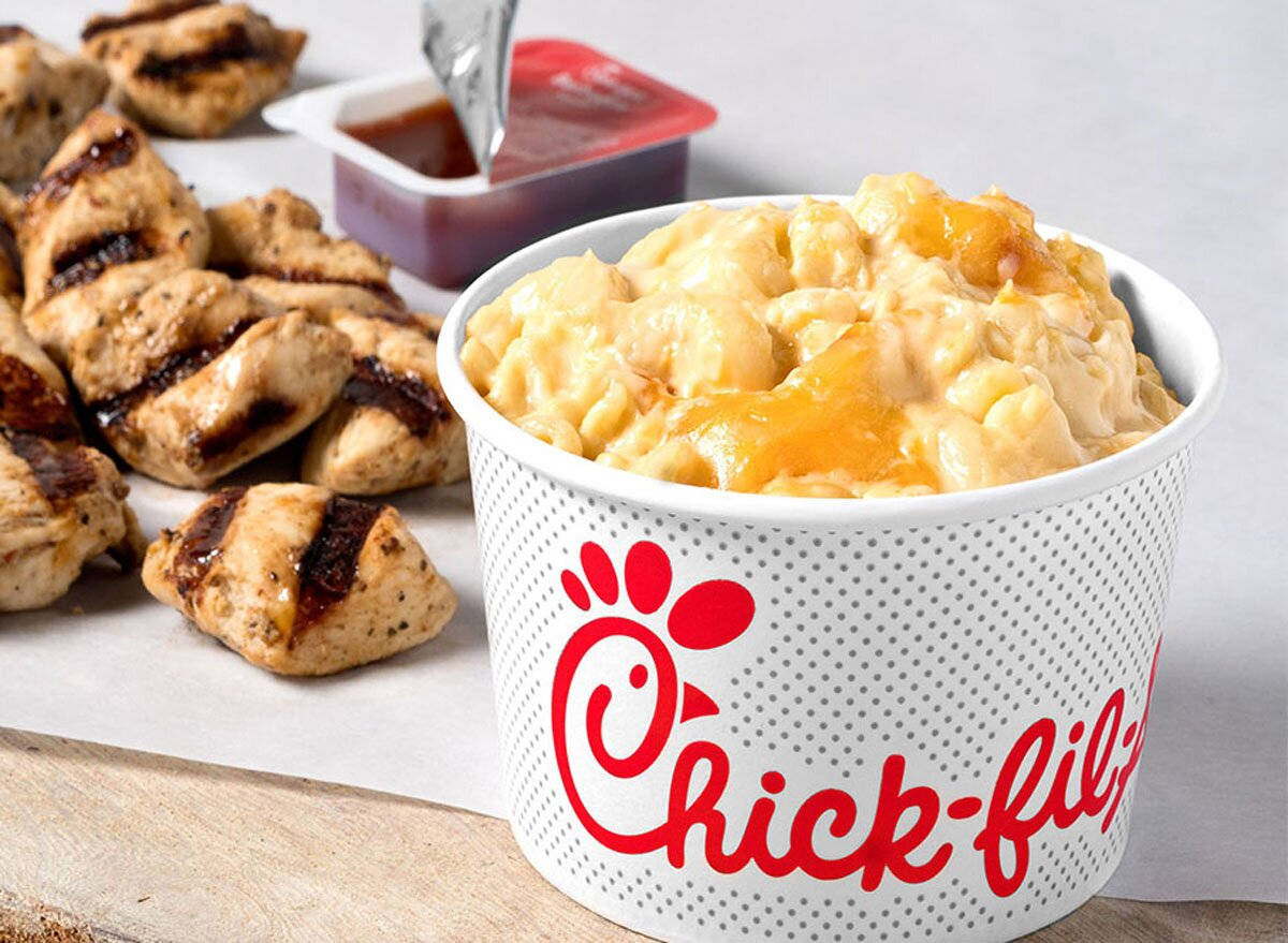 標題：品嚐 Chick-Fil-A 奶油芝士通心粉的美味 壁紙 — 一個白色Chick-fil-A桶裝滿了奶油通心粉和芝士，旁邊有烤雞肉塊和蘸醬。