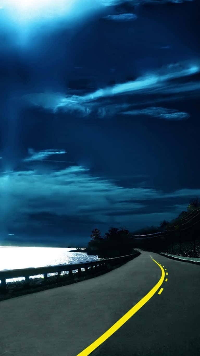 夜晚一條蜿蜒的海岸公路，帶有明亮的黃線和上方發光的雲朵。