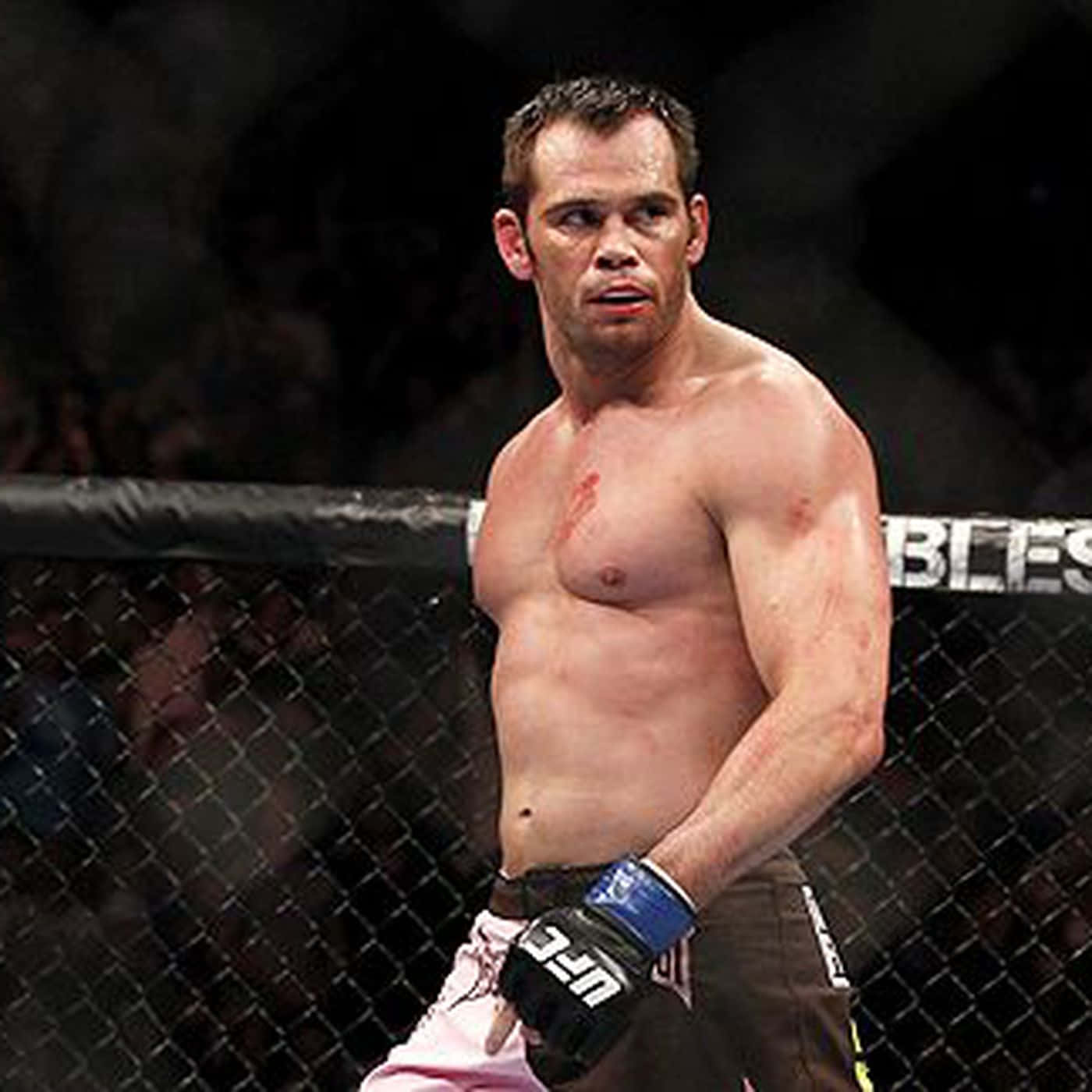 一名血跡斑斑的MMA戰士在比賽後站在八角籠內。