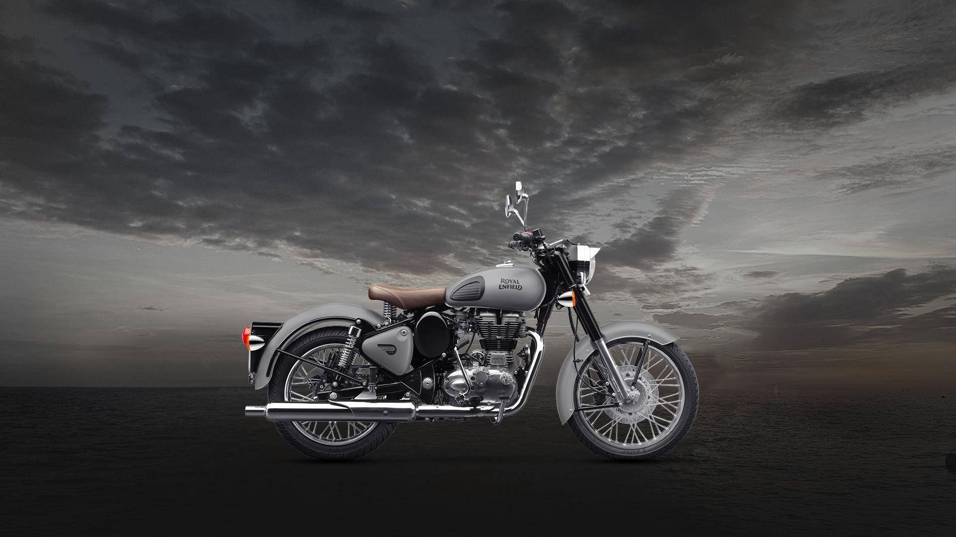 標題：經典350皇家恩菲德高畫質 壁紙 — 一輛銀色 Royal Enfield 電單車獨自站在黑暗的平原上，黃昏時分天空多雲，氣氛戲劇化。