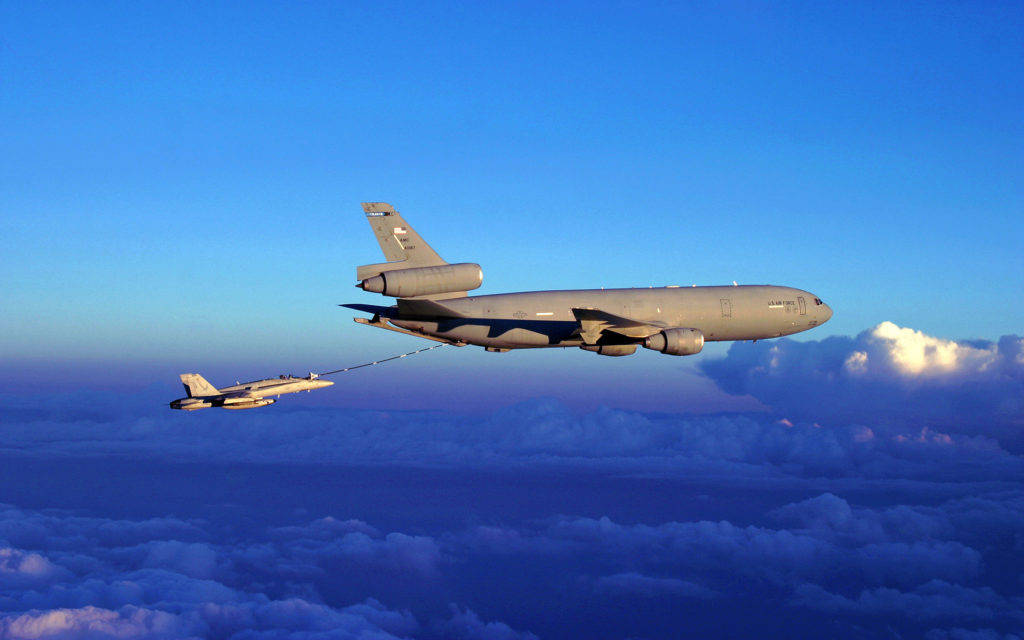 標題：「翱翔高空：空軍強悍戰機」 壁紙 — 一架軍用加油機在日落時分於雲海之上為戰鬥機加油。