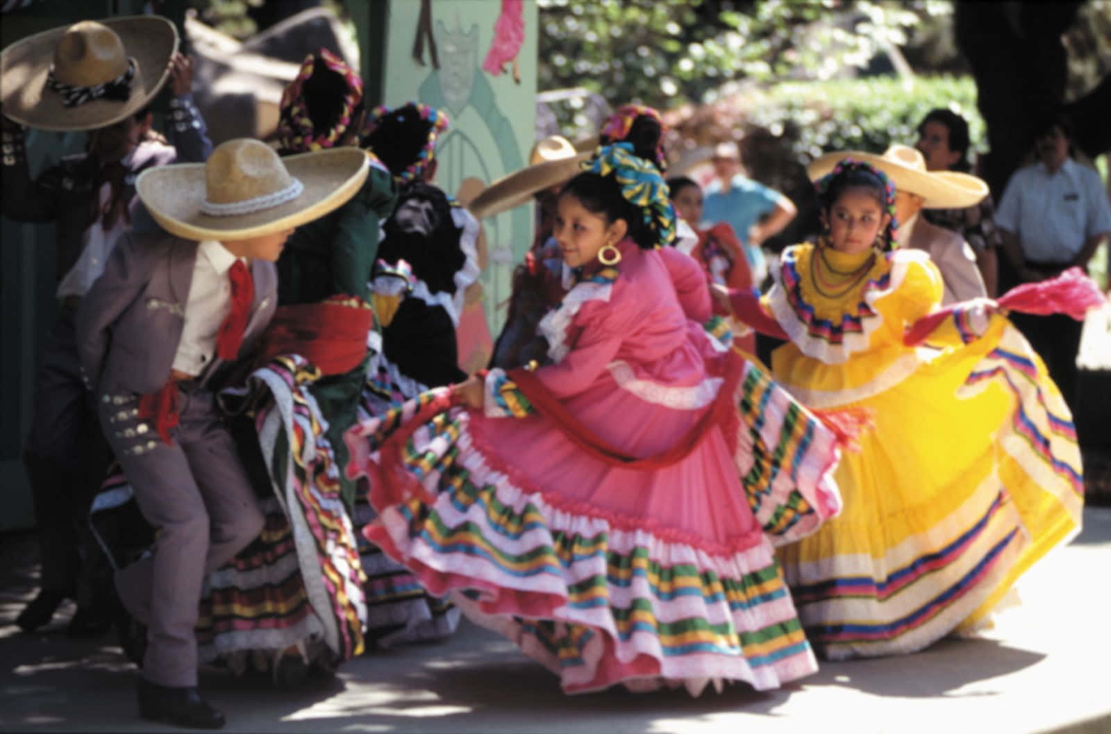 標題：色彩繽紛的 Cinco de Mayo 庆祝活動 壁紙 — 色彩繽紛的傳統服飾舞者在明亮的日光下表演生動的民間舞蹈。