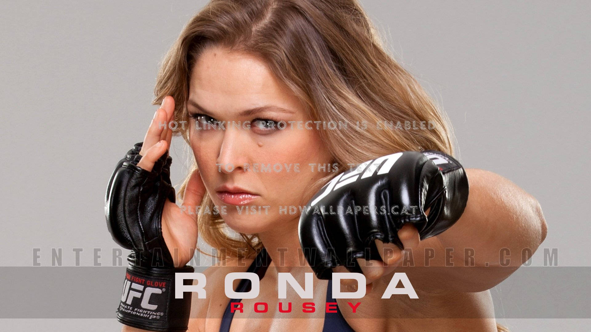 女MMA拳手Ronda Rousey戴著黑色手套在攝影棚中擺出強烈姿勢。