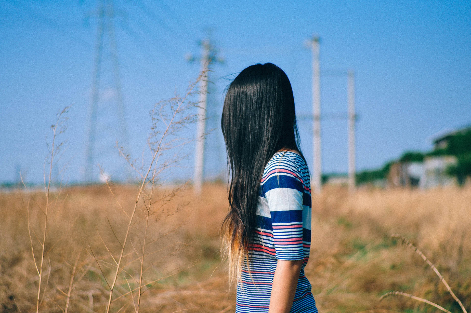 身穿條紋襯衫的女性站在夕陽下的乾草田野中