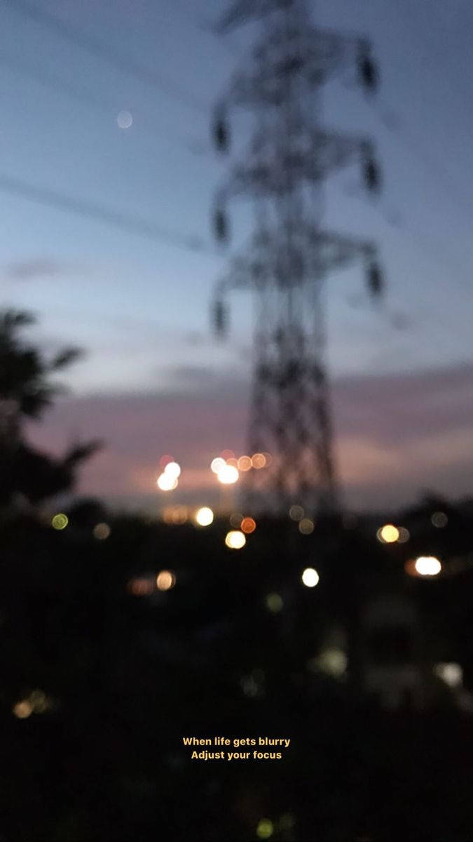 模糊人生金句深色背景 壁紙 — 模糊的黃昏場景，一條高聳的電線在漸變天空下，下方有散景燈光。