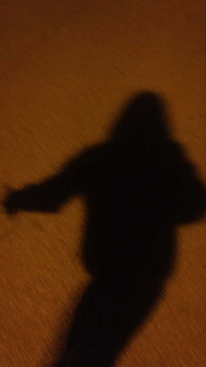夜間在橙色牆上投射陰影的人的模糊剪影。