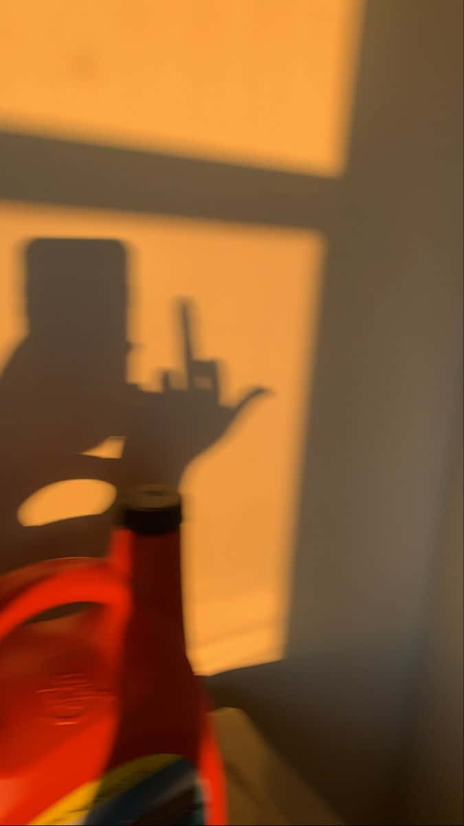 紅色瓶子在照明牆上投射出人拿電話的影子。