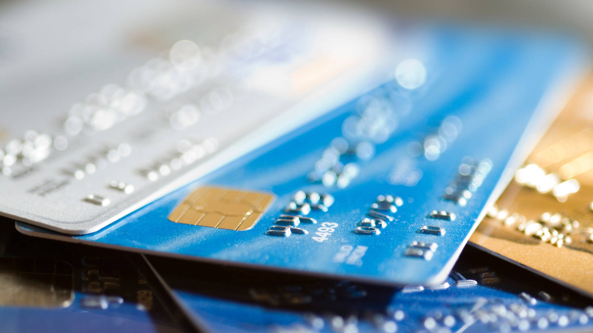藍色、銀色和金色的信用卡和扣賬卡疊放。