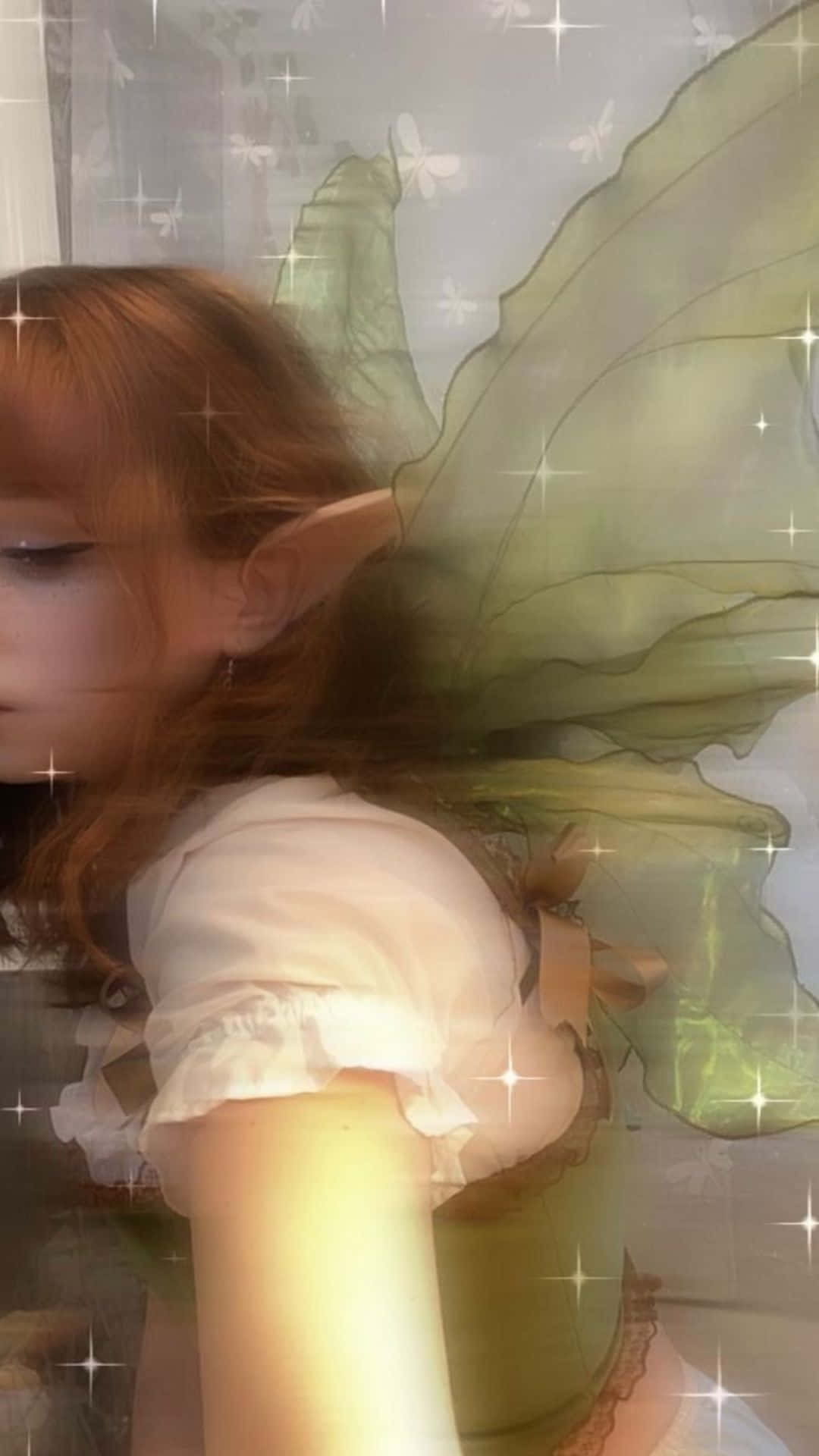 模糊美學精靈系背景 壁紙 — 一位年輕女性，擁有精靈耳朵和半透明綠色翅膀，在閃爍的發光窗戶前柔和地擺姿勢。