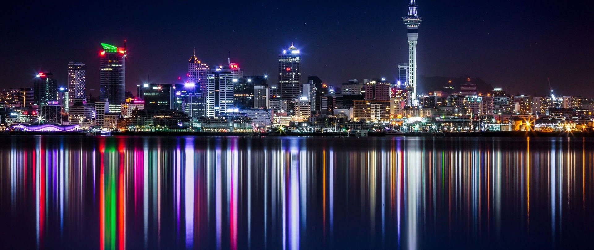 星空下，色彩繽紛的燈光倒映在水中的夜間城市景觀