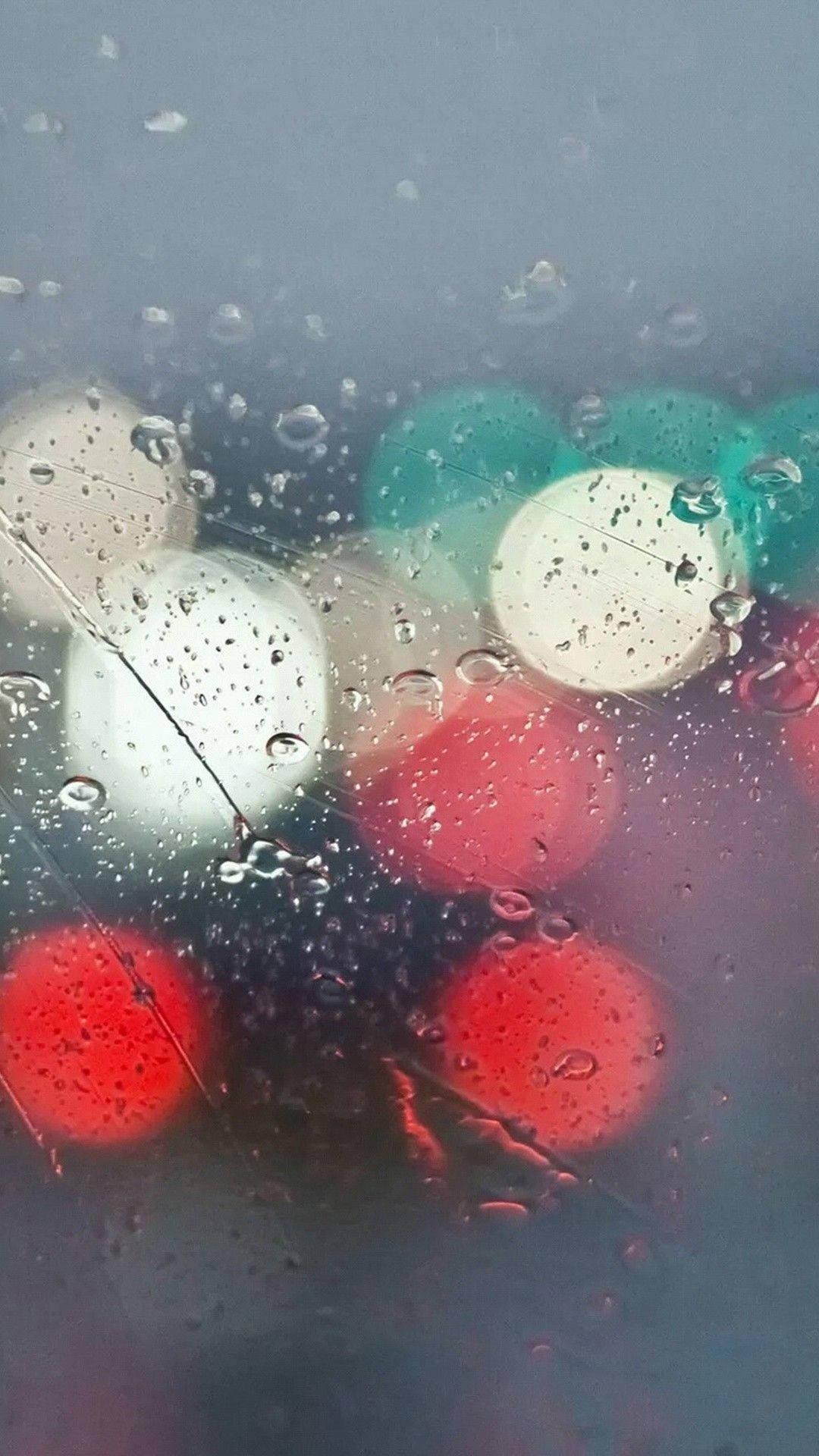 夜晚窗外模糊的彩色燈光和窗上的雨滴。
