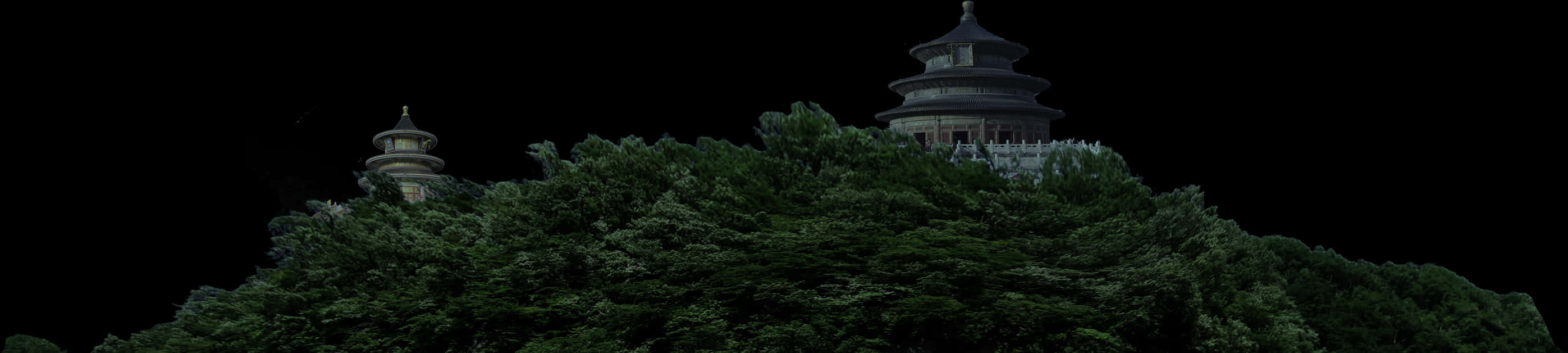 樹頂上的神殿夜景 壁紙 — 兩座傳統寶塔從茂密森林覆蓋的山丘上聳立，背景為純黑色。