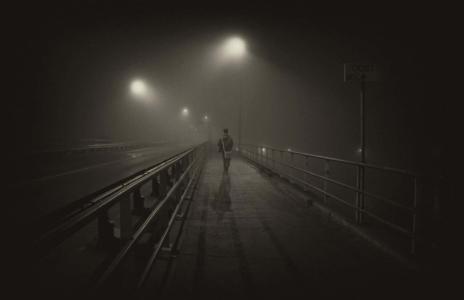 橋上行人離港 壁紙 — 一個孤獨的身影在夜晚的霧橋上獨自行走，發光的街燈投下長長的影子。