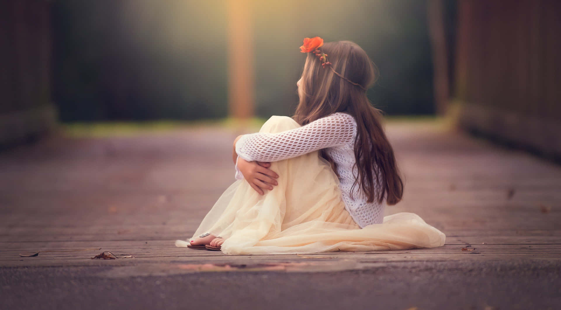 一個穿著奶油色連衣裙的小女孩獨自坐在木路上，頭髮上插著一朵花。
