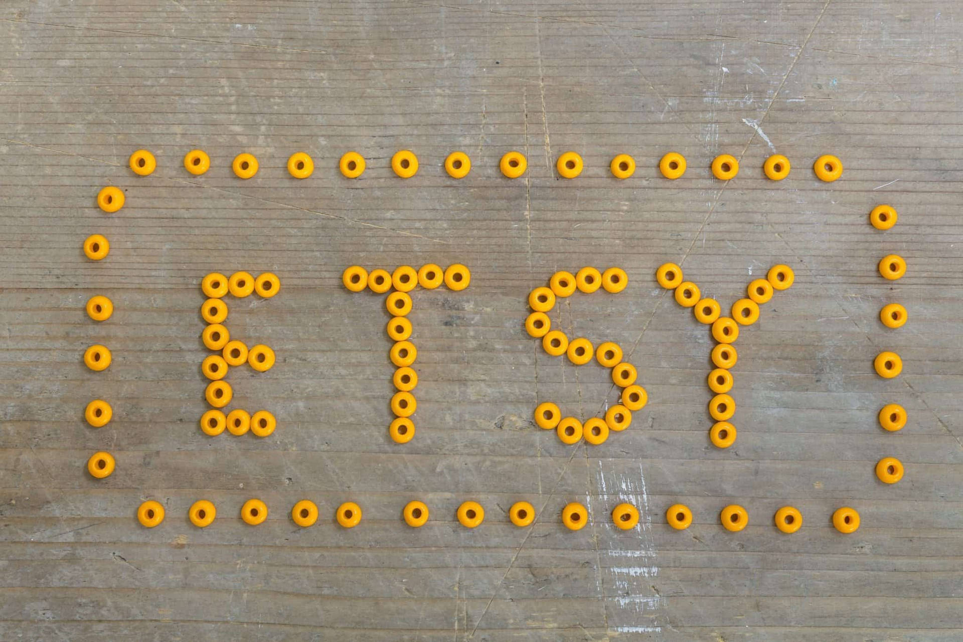 黃色珠子喺木背景上拼出Etsy。