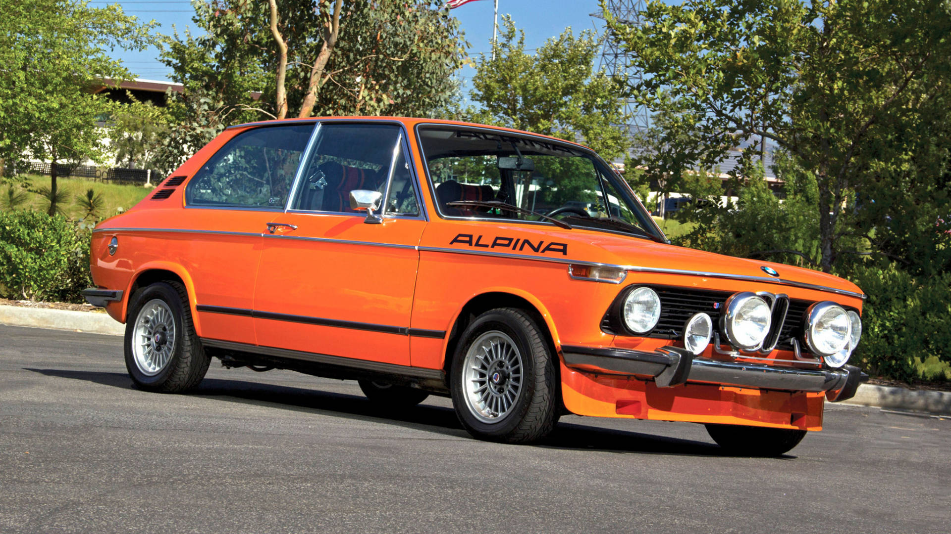 橙色Alpina BMW經典汽車在陽光明媚的日子停放在戶外。