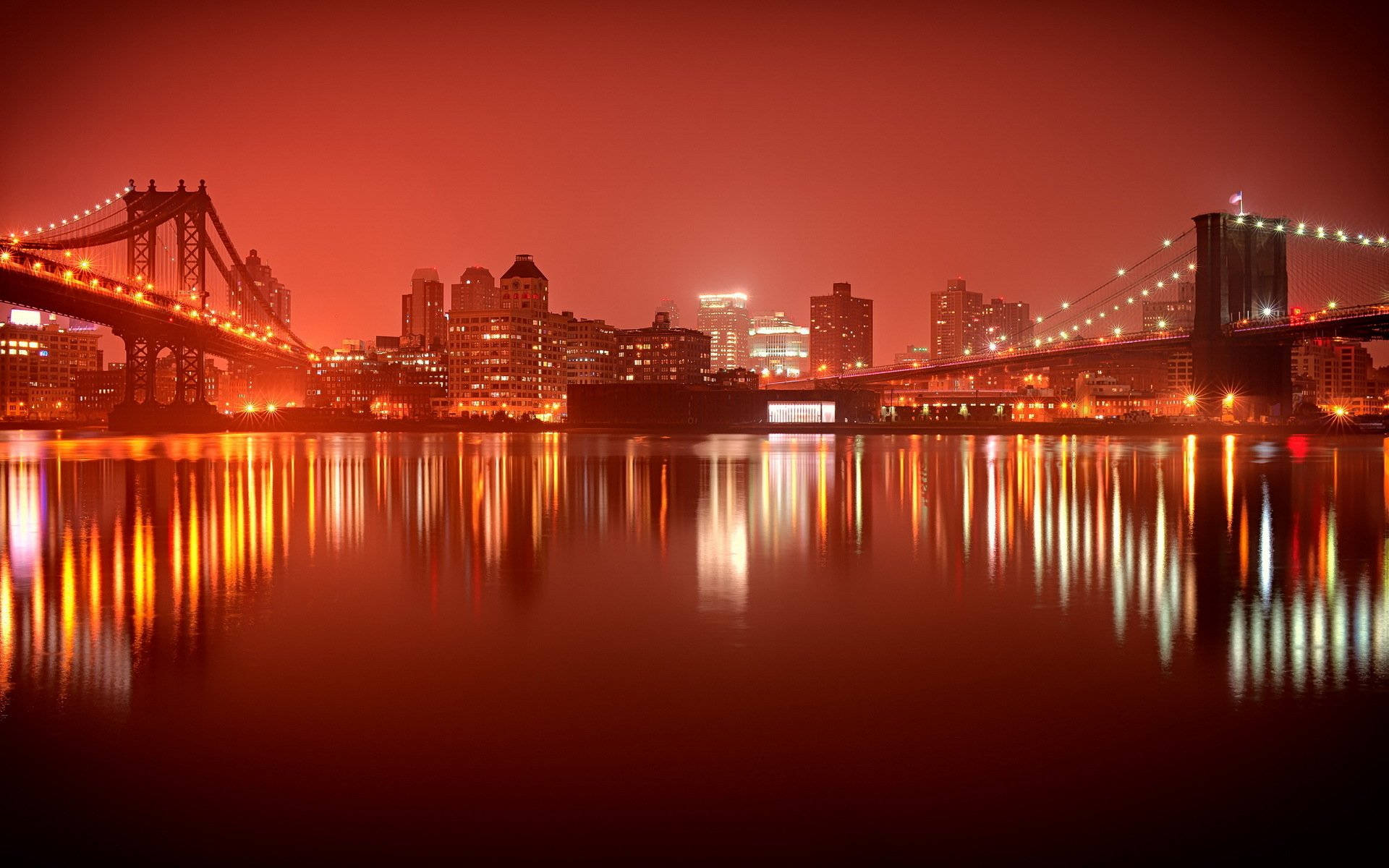 橙城平行橋樑倒影如畫 壁紙 — 充滿活力的紅色調夜景城市景觀，兩座燈光璀璨的橋樑倒映在平靜的水面上。