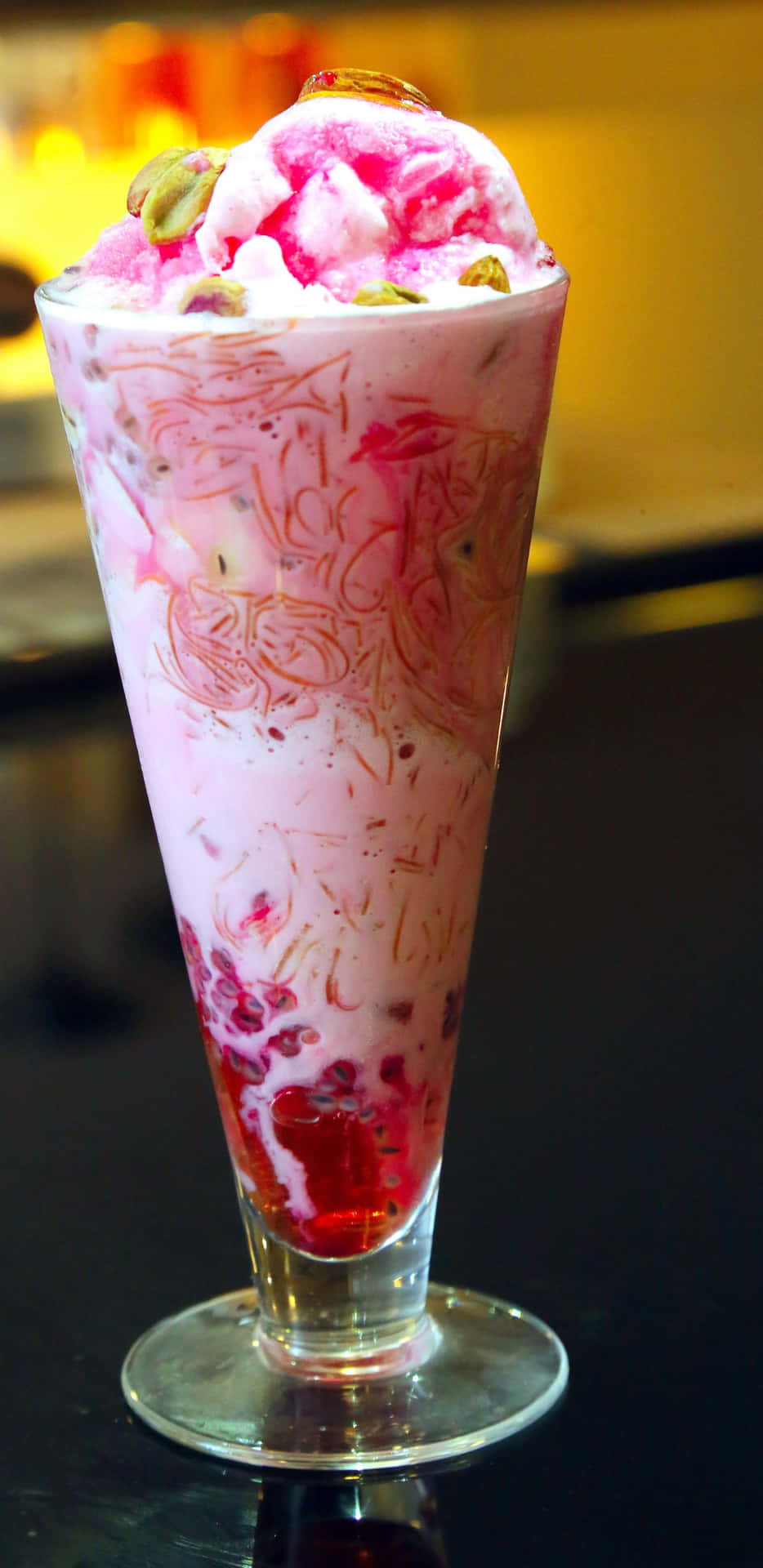 高身杯中的粉紅色庫爾菲甜品，配上開心果和金箔。