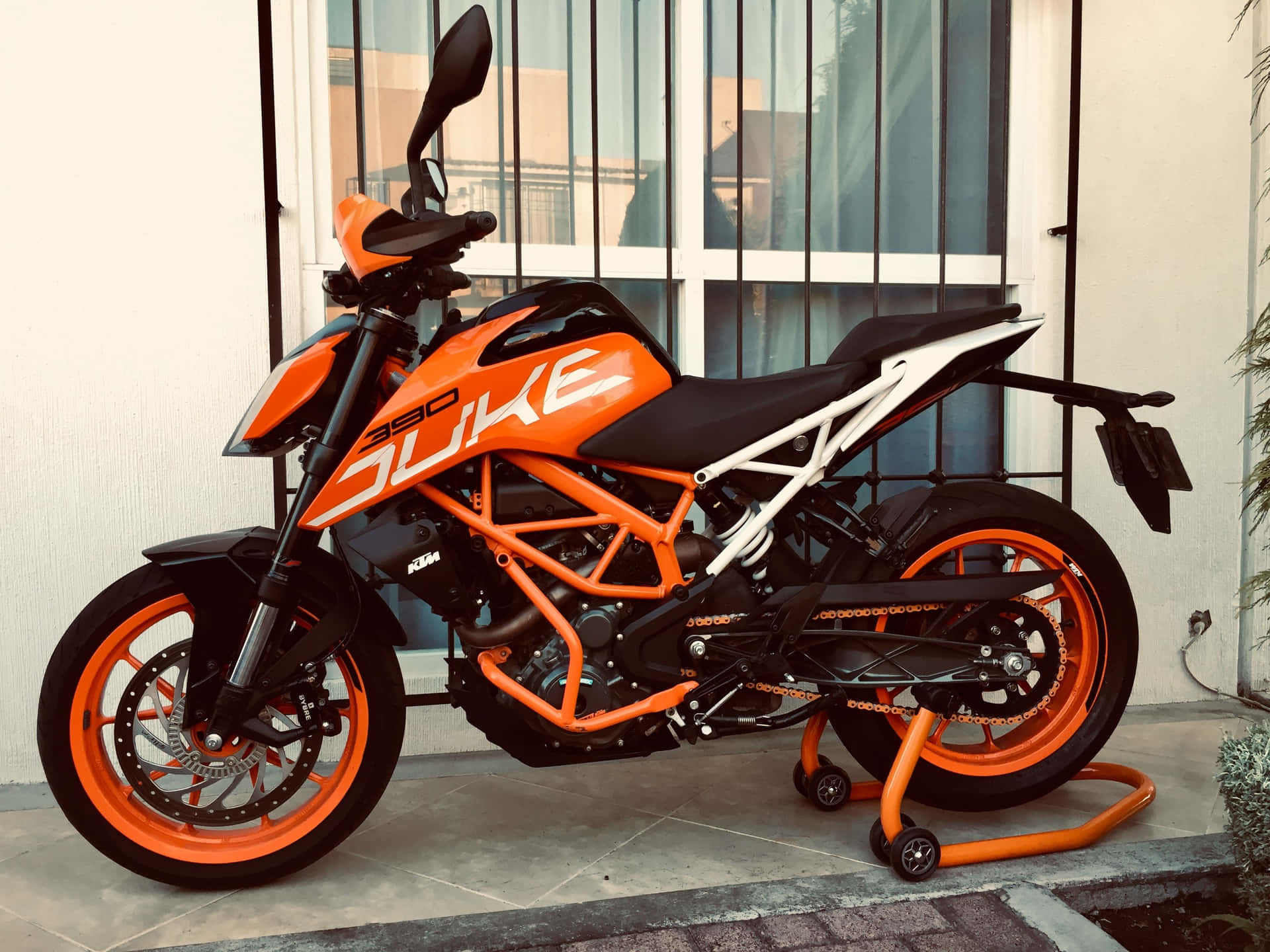 橙色和黑色的KTM 390 Duke電單車停泊在瓷磚庭院上。