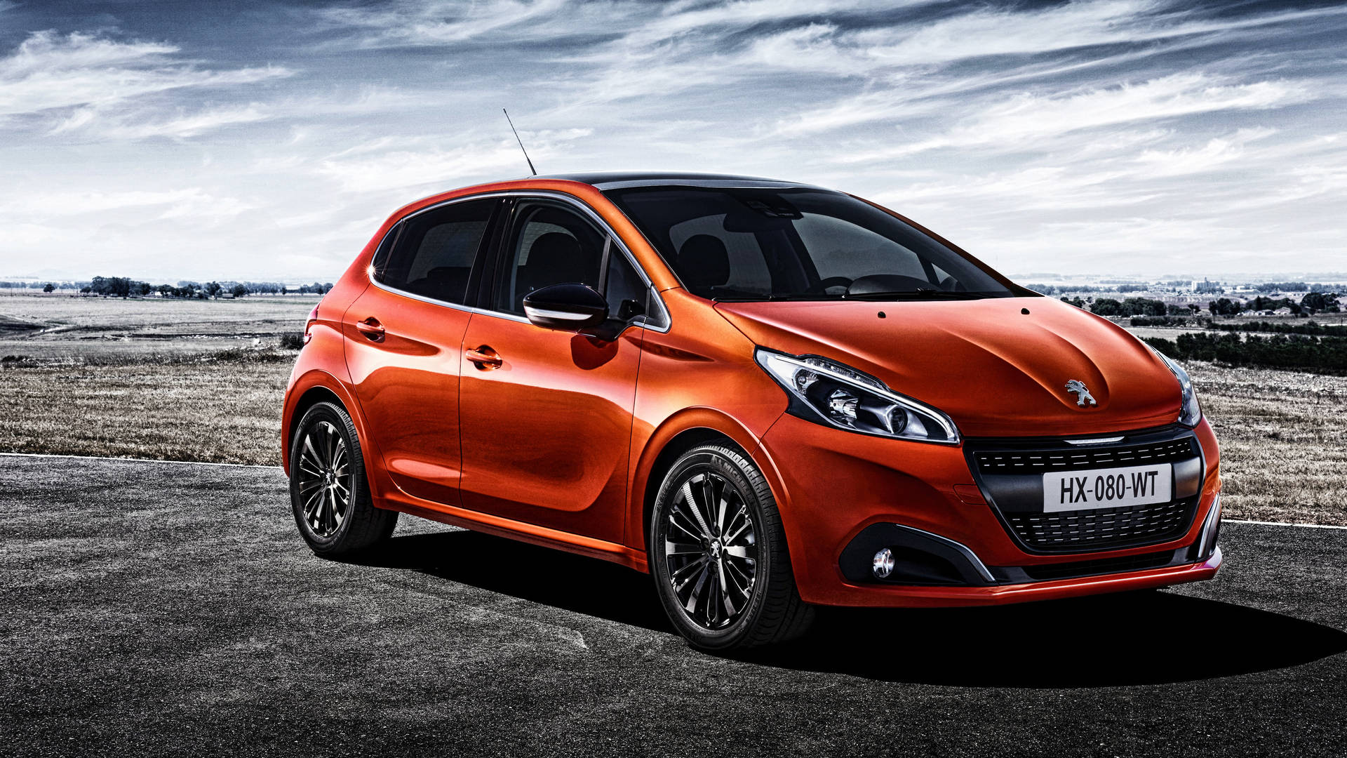 橙色Peugeot 208停泊在瀝青路上，背景為多雲天空。