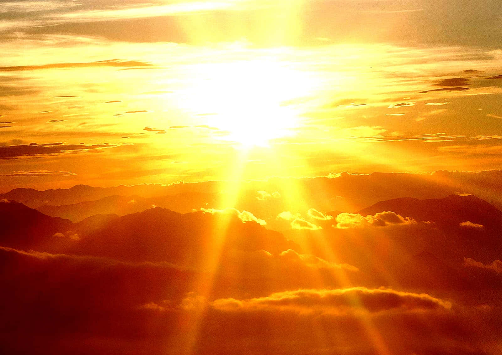 夕陽映照山巒，金色光芒穿透雲層。