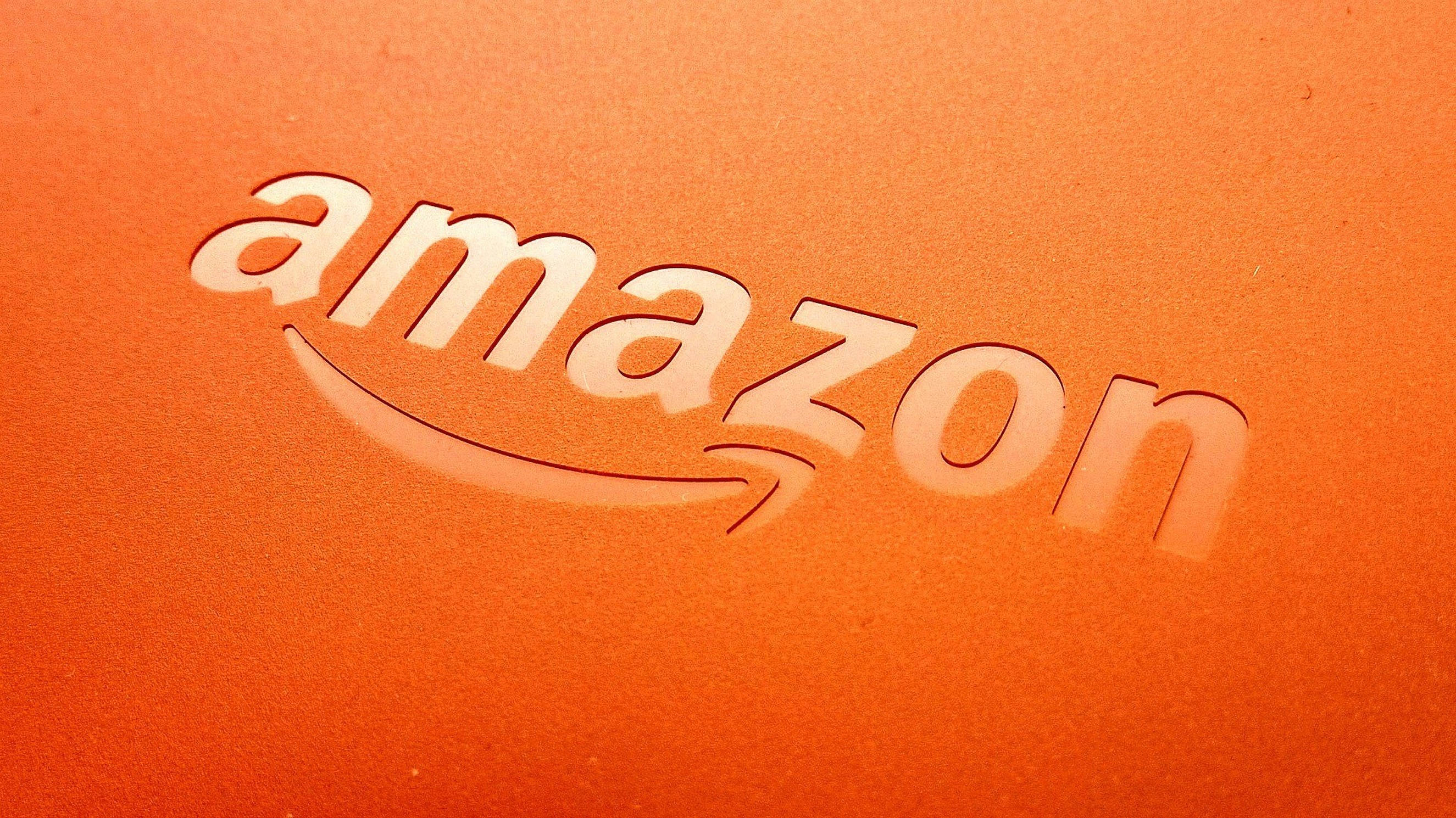 橙色壓紋Amazon標誌 壁紙 — 柔軟燈光下，紋理橙色物料上壓印的Amazon標誌特寫。