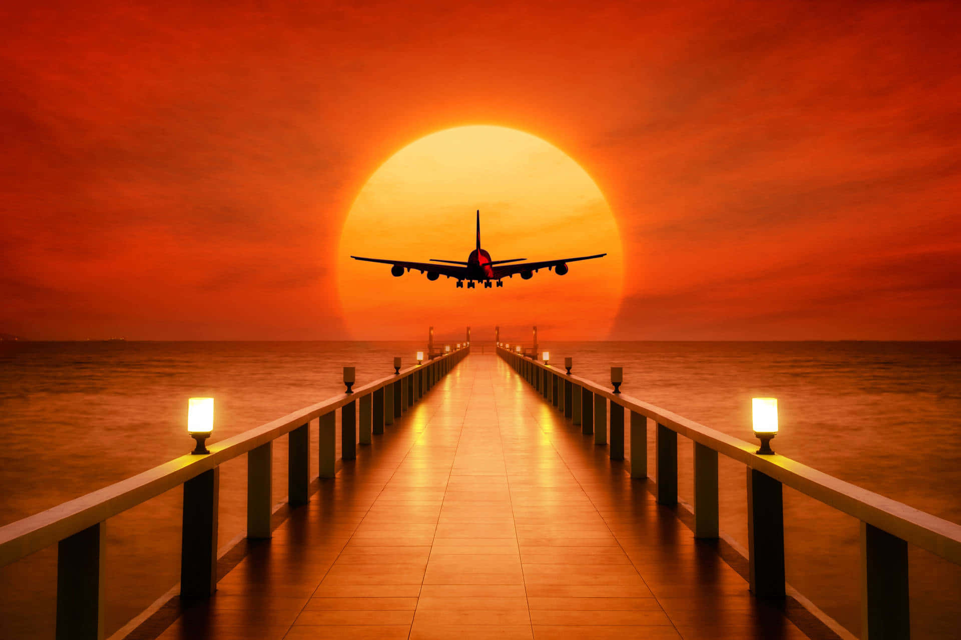 橙色壯麗日落飛機背景 壁紙 — 一架飛機在巨大的橙色太陽襯托下形成剪影，在日落時低飛過發光的碼頭。