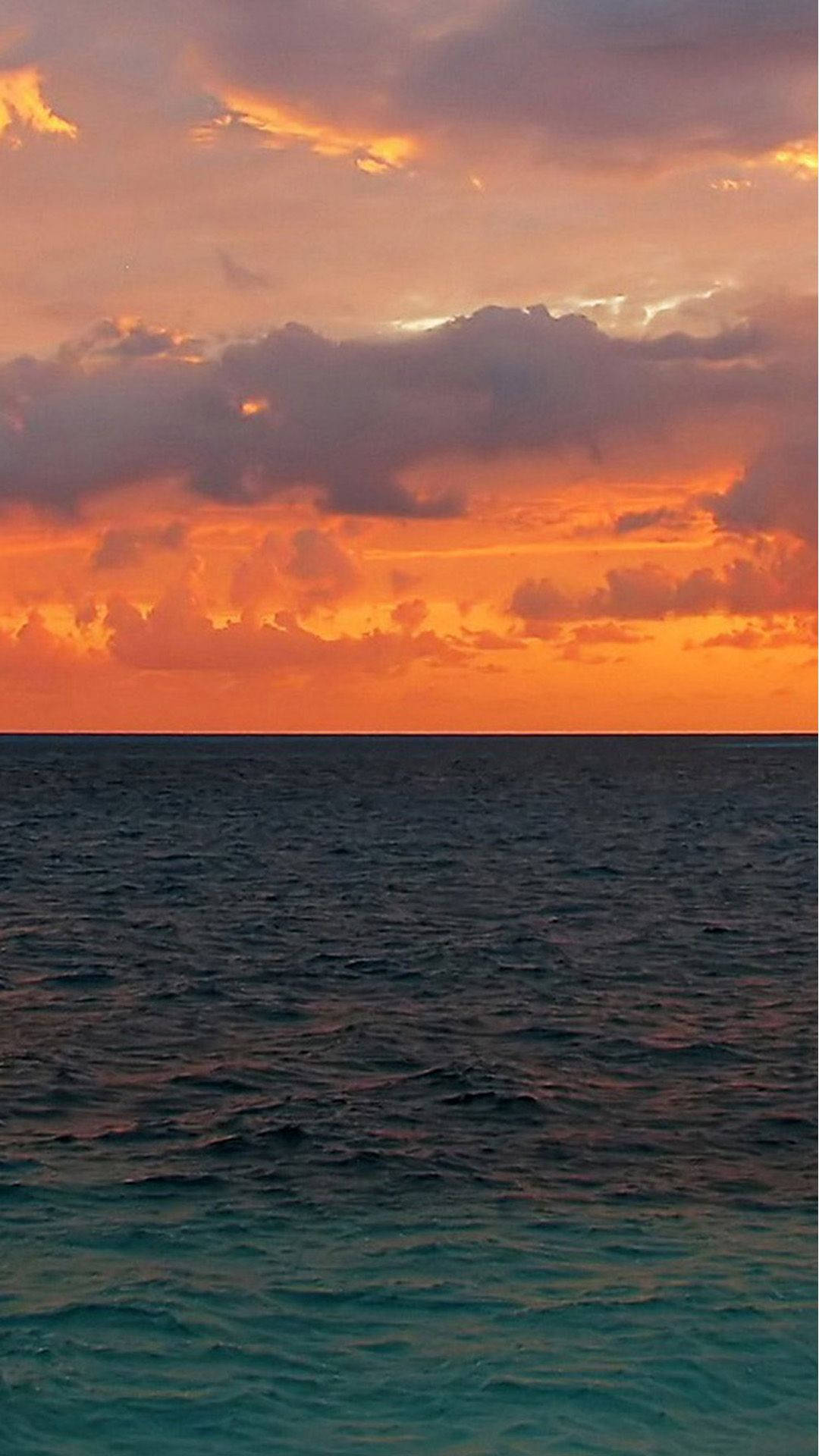 平靜海洋上 vibrant 的日落，橙色雲彩和碧綠海水。