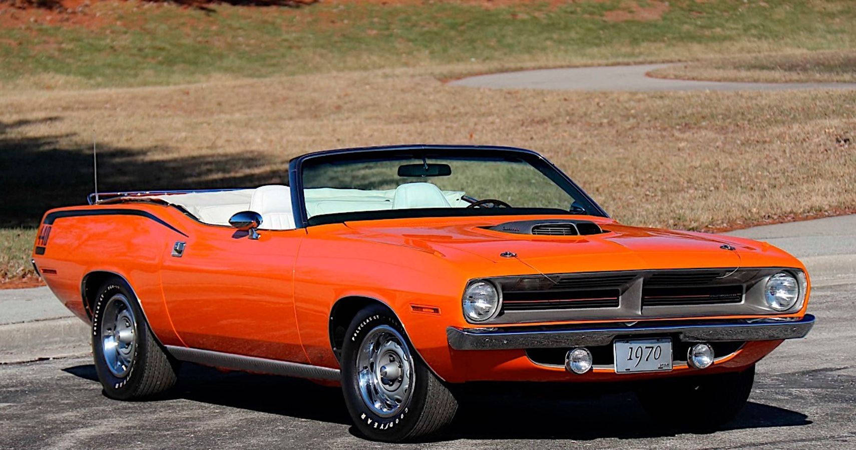 橙色普利茅斯巴雷卡達敞篷車 壁紙 — 一架充滿活力的橙色1970年Dodge Challenger開篷車停泊在瀝青路上，背景是長滿草的山丘。