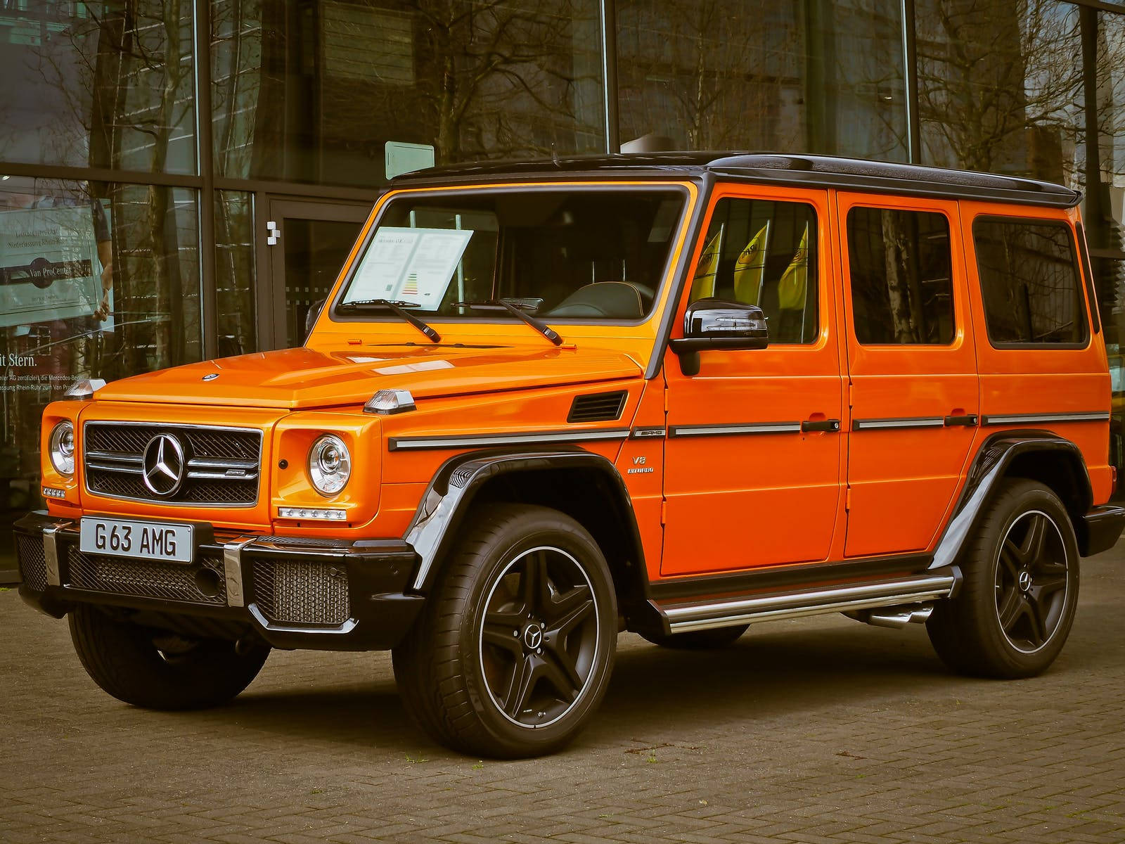 橙色 Mercedes G63 AMG SUV 停泊在玻璃建築外。