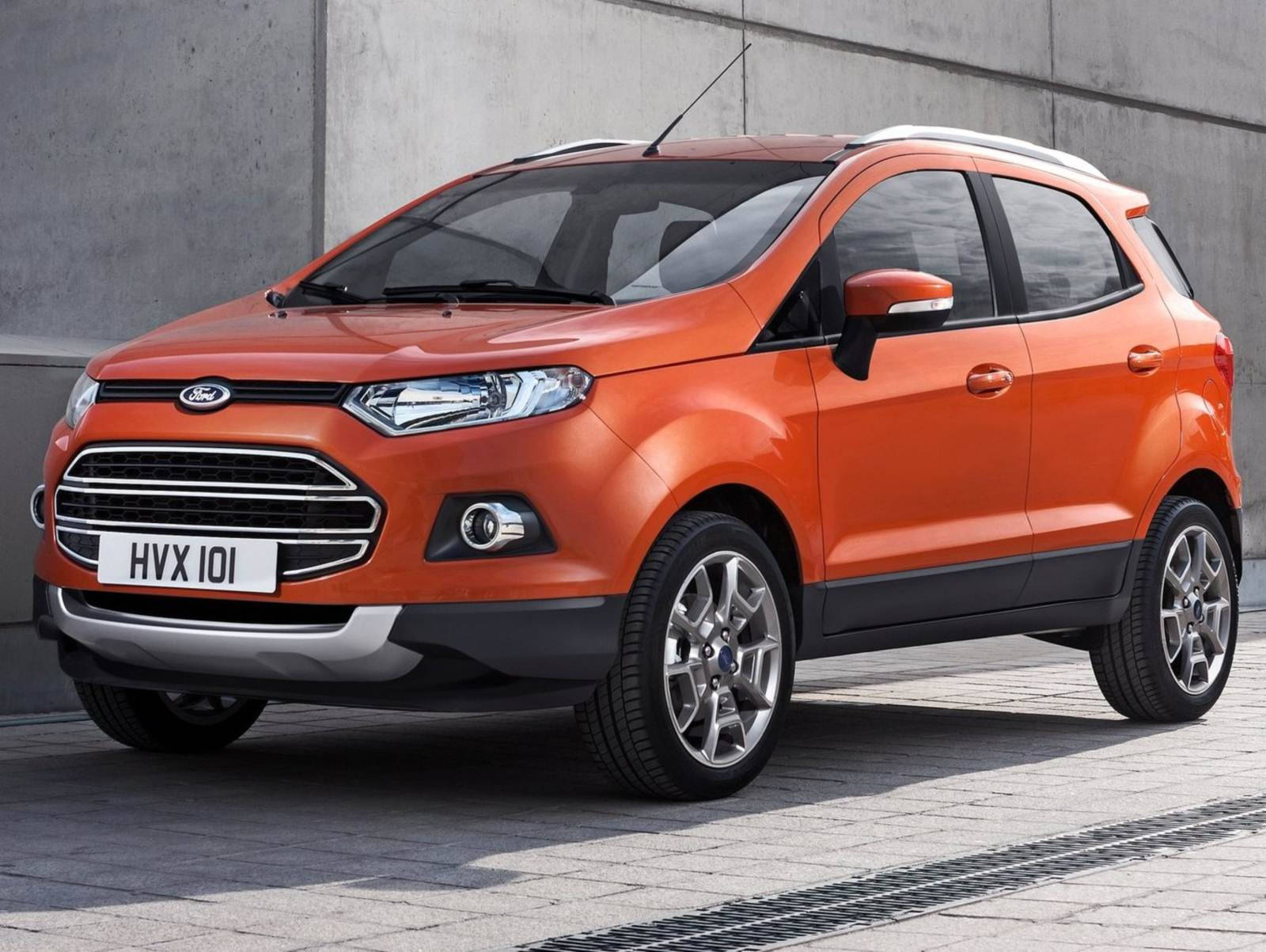 橙色福特EcoSport SUV停泊在混凝土牆附近的行人路上。
