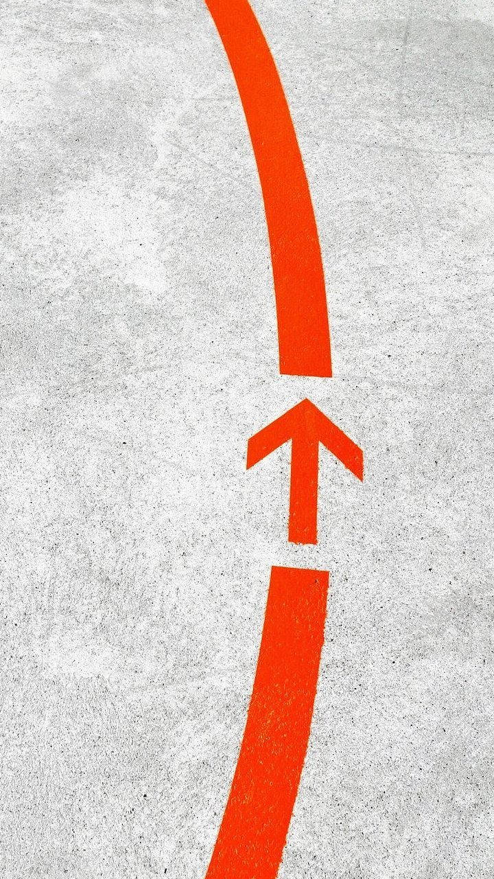 灰色混凝土表面上畫的橙色方向箭頭