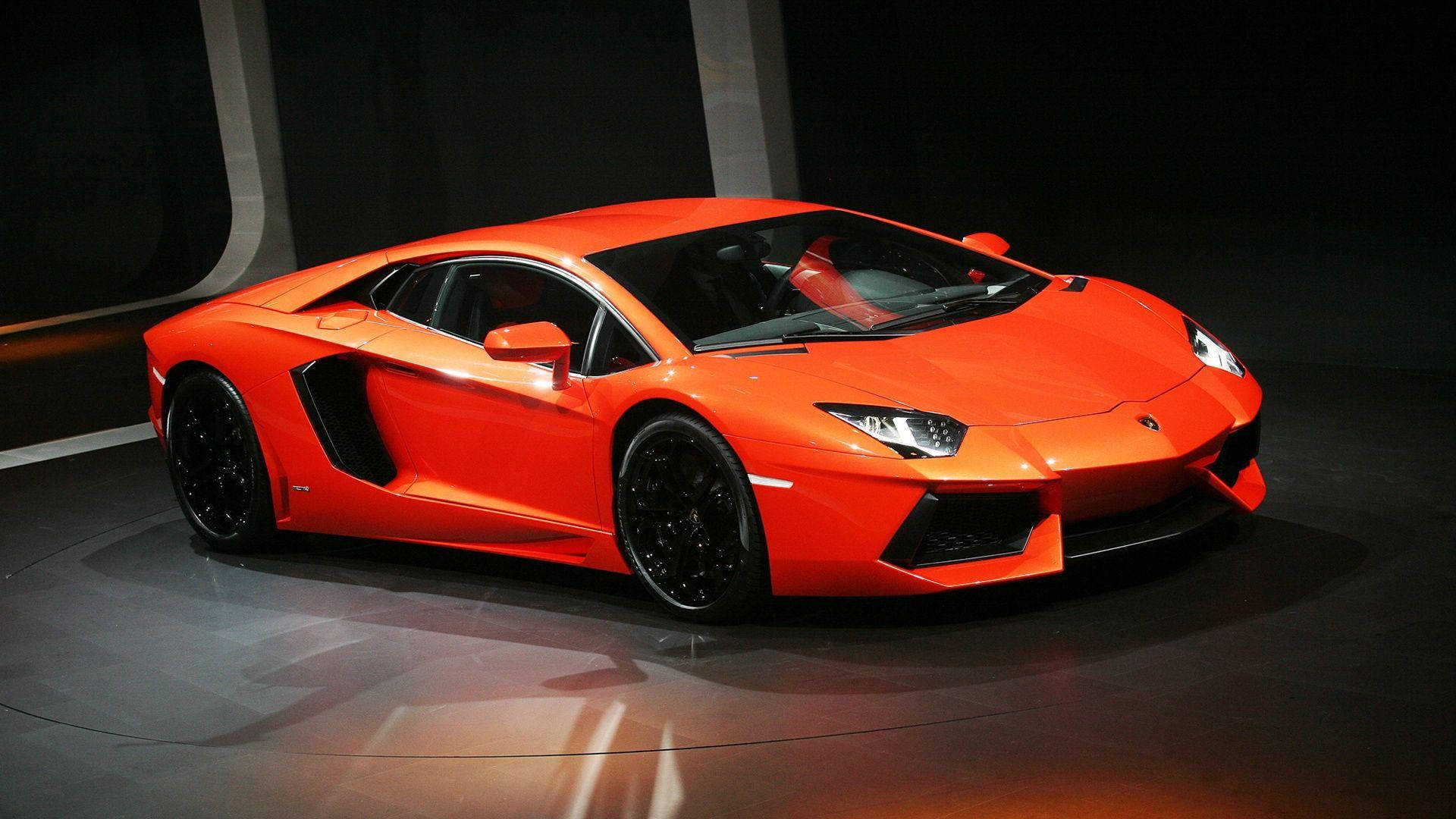 橙色蘭博基尼Aventador全高清汽車壁紙 壁紙 — 一輛充滿活力的橙色林寶堅尼Aventador跑車在黑暗的反光舞台上，在攝影棚燈光下閃閃發光。