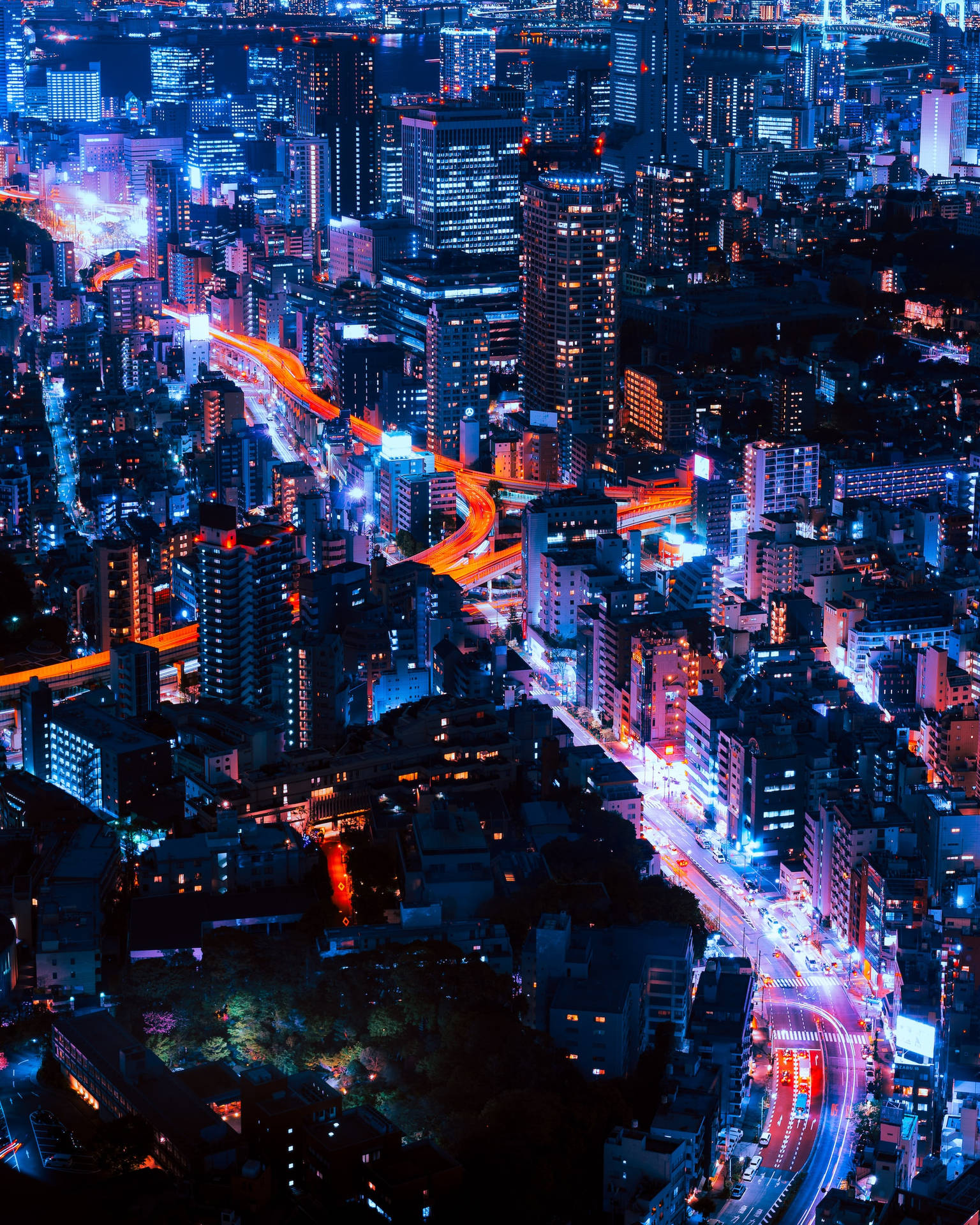 夜晚城市鳥瞰圖，霓虹燈和交通痕跡閃爍。