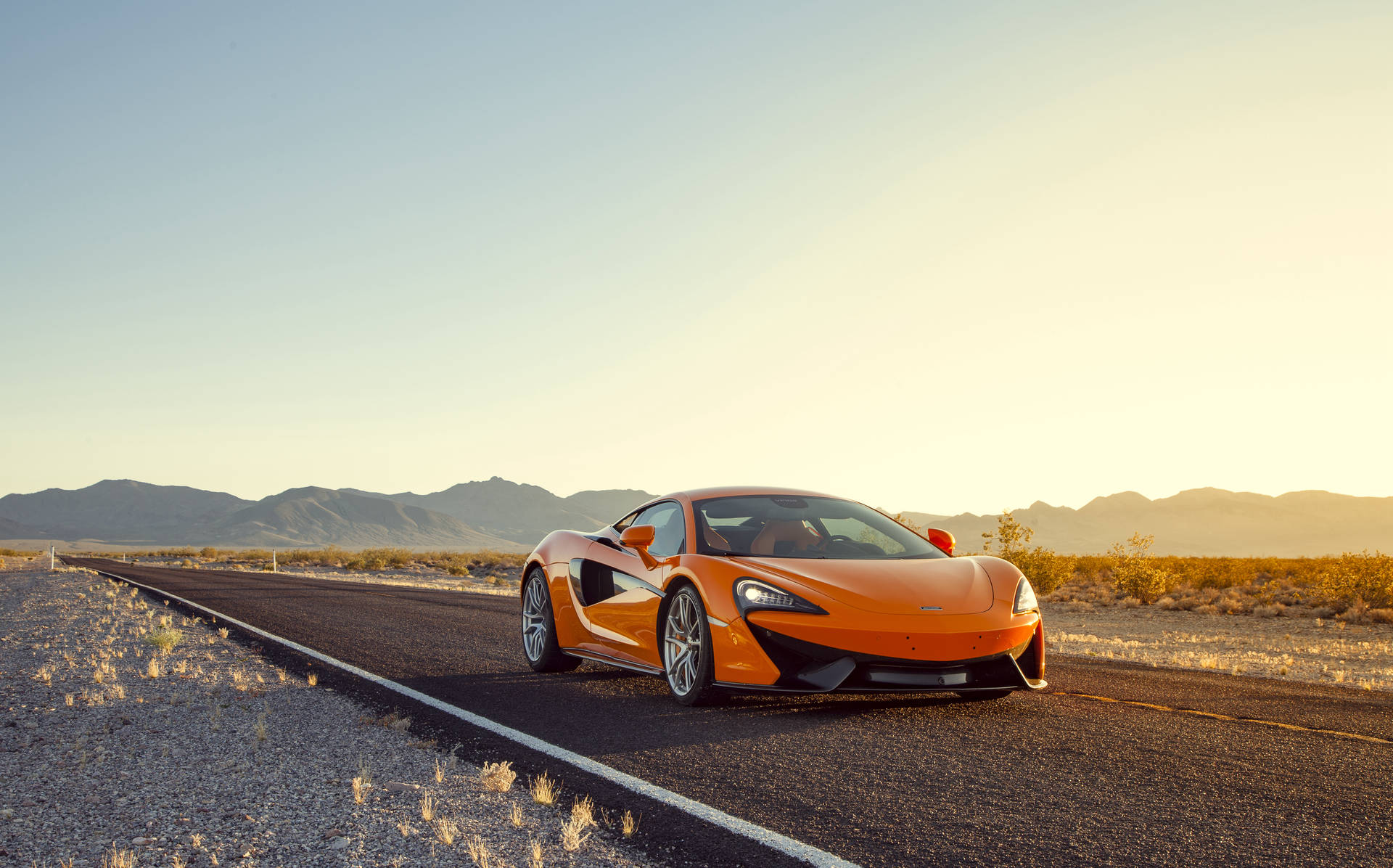 日落時沙漠高速公路上的橙色McLaren