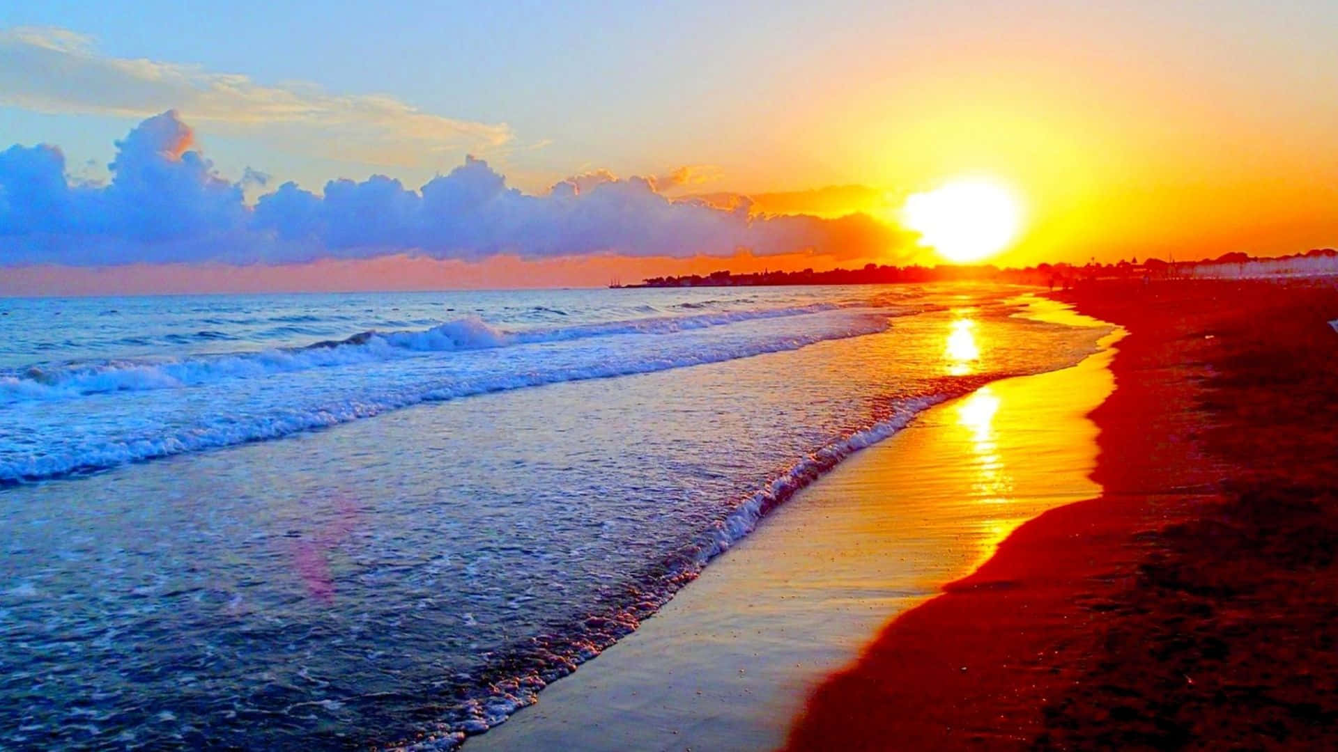 橙黃海景特寫 壁紙 — 夕陽燦爛，將海洋和海灘染成火橙色和深藍色，海浪拍打著海岸。