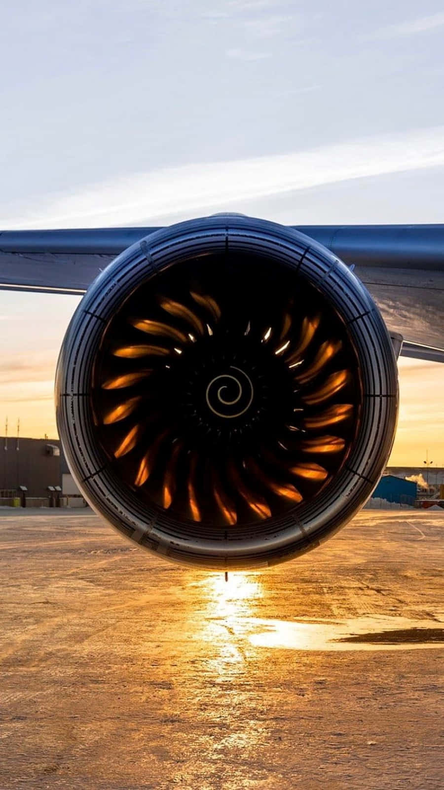 Jet Engine 桌布 壁紙 — 機場停機坪上，噴射引擎在夕陽天空下發出溫暖光芒的特寫。