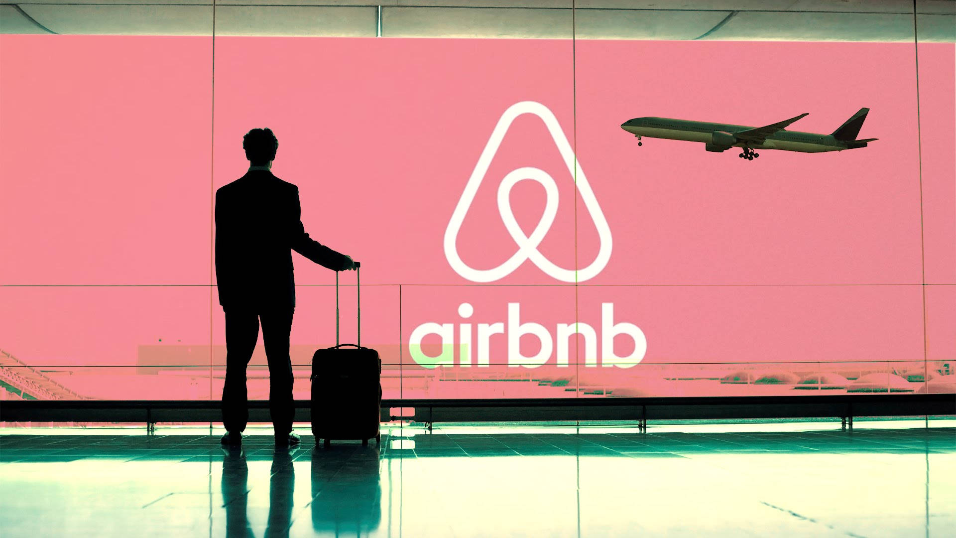 男人拎住手提箱企喺機場客運大樓嘅大型Airbnb標誌前面，飛機喺上空飛過。