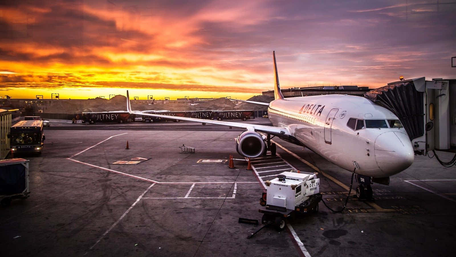 達美航空飛機在機場閘口，日落色彩鮮豔。