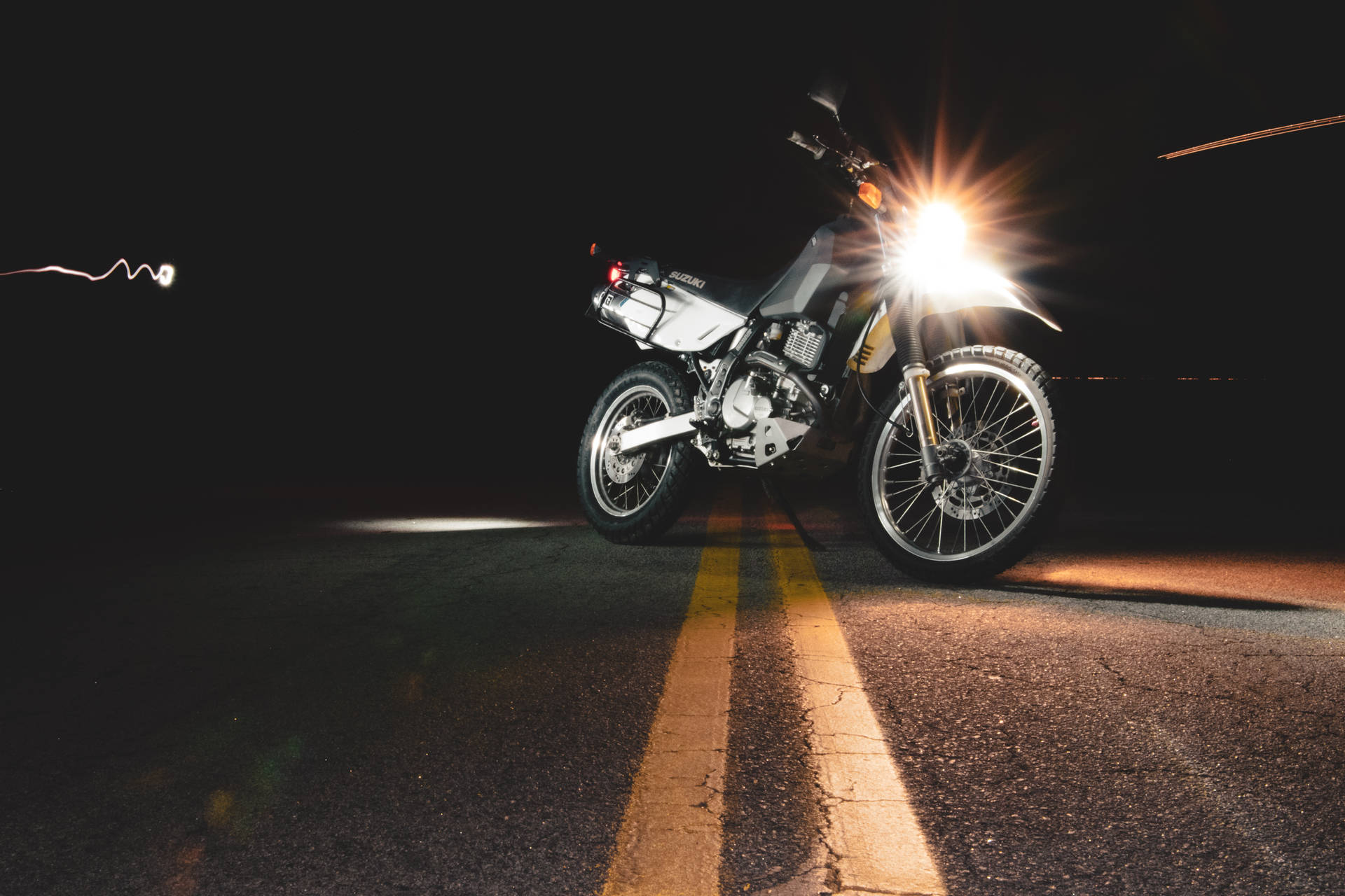 夜間黑暗道路上帶有明亮頭燈的銀色電單車，帶有動態模糊效果。