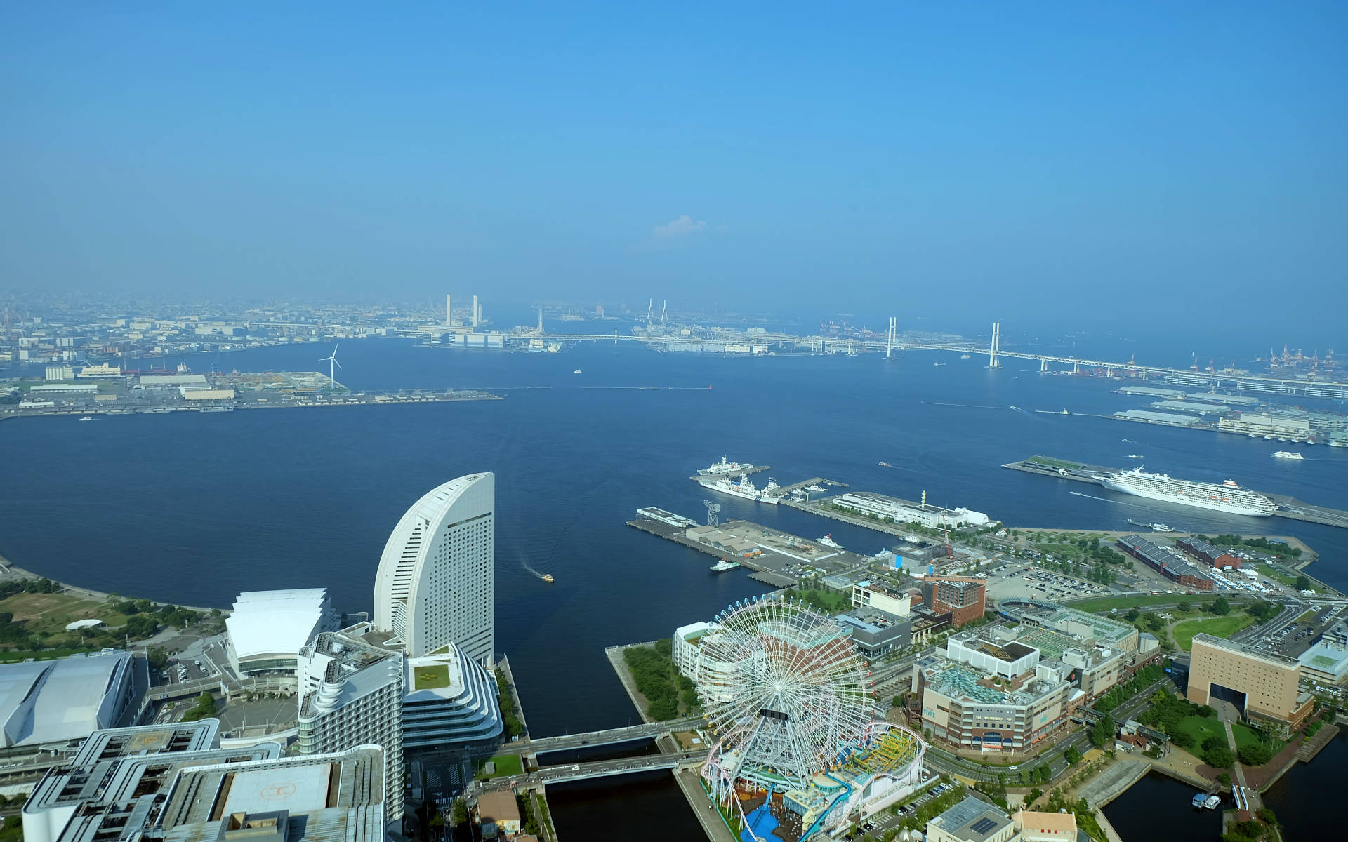 橫濱城市高角度俯瞰 壁紙 — 東京灣的鳥瞰圖，有郵輪碼頭、色彩繽紛的摩天輪和現代建築，在晴朗的藍天下。