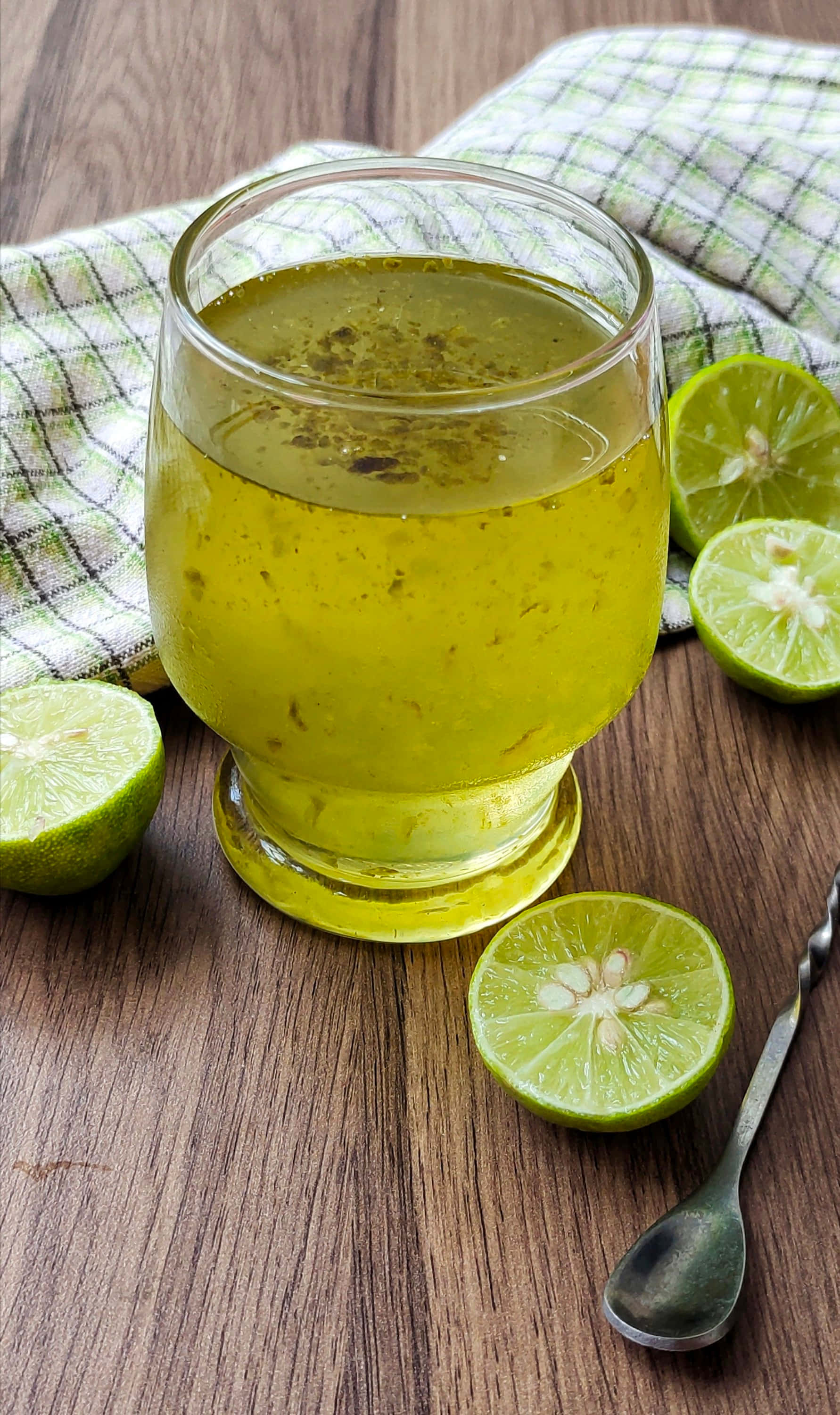 檸檬葉果汁與切片 壁紙 — 一杯清爽的青檸飲品，配上新鮮青檸片，放在木桌上，旁邊有格仔餐巾和匙羹。