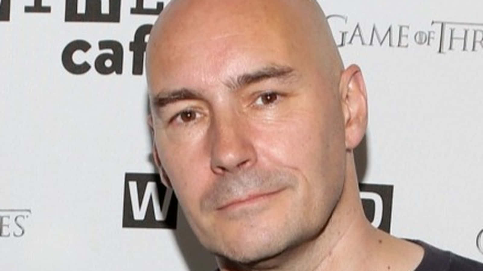 Grant Morrison 桌布 壁紙 — 權力遊戲活動中一名光頭男子面無表情的特寫肖像。