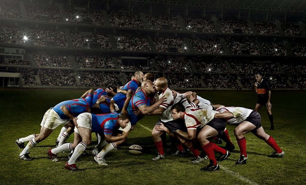 Rugby 桌布 壁紙 — 欖球球員在球場燈光下激烈爭球，全場觀眾專注觀看。