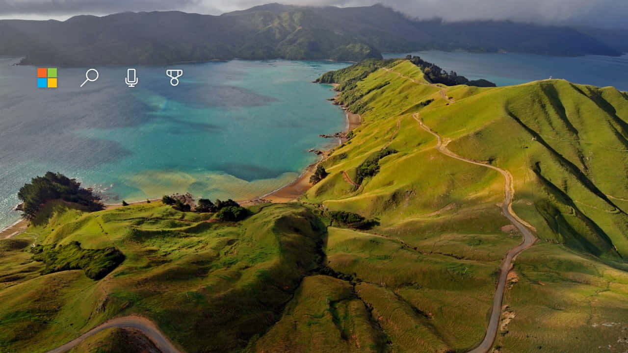 蜿蜒的道路沿著翠綠的山丘，旁邊是碧綠的海水，天空多雲